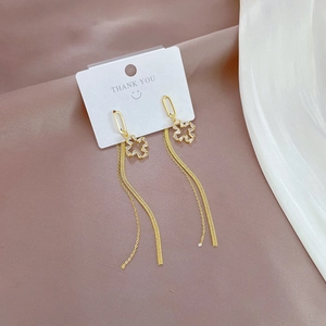 Detail of gold clover earrings with sparkling diamonds and elegant long tassels