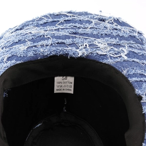 Detail view of cotton washing label and size tag inside blue washed denim cowboy hat