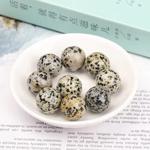 Polished Dalmatian Jasper spheres set in a white porcelain dish with book background