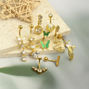Close-up of gold-plated belly rings with zircon inlays featuring butterfly and snake shapes