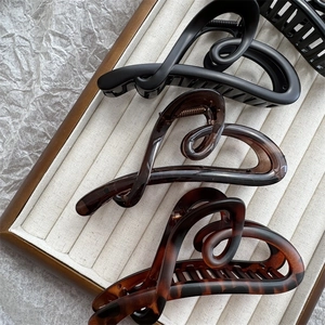 Three elegant heart-shaped hair claw clips in matte black, brown, and tortoiseshell finish