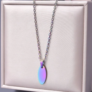 Macro detail of oval stainless steel pendant with purple iridescent 18k gold plating