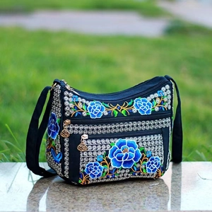 Detail of floral embroidery on a black canvas bag with golden zipper pullers