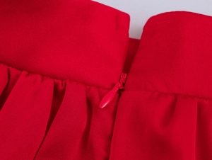 Détail du short rouge montrant la fermeture éclair à la taille et le tissu plissé