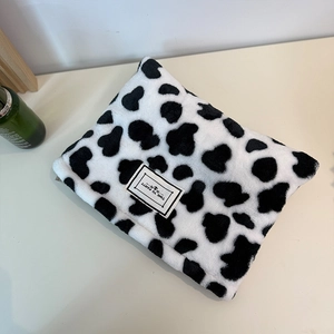 Plush cow print coin purse with soft texture and Time to Party label on beige surface