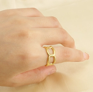 Detail of adjustable 18k gold chain texture ring worn on finger over silk background