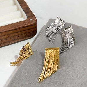 Elegant gold and silver metallic tassel earrings displayed on a grey premium jewelry pad