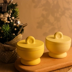 Contenitori rotondi giallo brillante con coperchi e manici su vassoio in legno