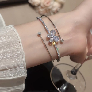 Dettaglio del bracciale a tre strati in argento con farfalla in zircone al polso