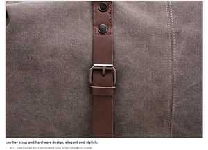 Detail of canvas travel bag featuring leather strap, metal rivets, and pin buckle closure