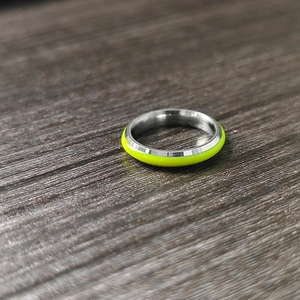 Close-up of luminous green coating on a polished stainless steel band with wood background