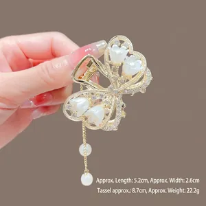 Vue détaillée de la pince à cheveux papillon doré avec pétales de lotus et perles