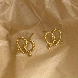 Close-up of golden pretzel shaped stud earrings with elegant twisted rope texture detail