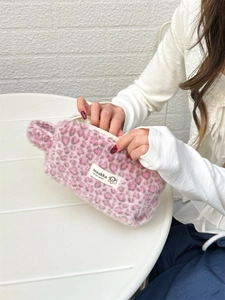 Detail of a plush pink leopard print makeup bag showing soft faux fur texture and brand label