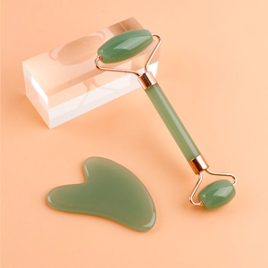 Doppelkopf-Gesichtsroller und herzförmiges Gua Sha-Set im rosa Hintergrund