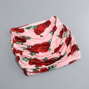 Détail d'une mini-jupe à fleurs avec roses rouges et fronces sur tissu satiné rose