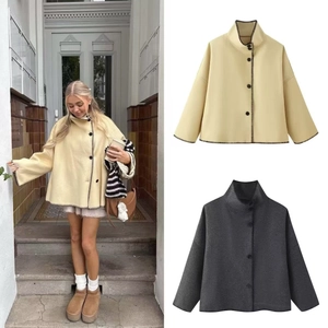 Detail view of high collar wool coat featuring contrast stitching and button closure