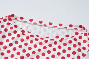 Gros plan du tissu blanc à pois rouges montrant le col et la texture douce du matériau