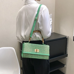 Detail of green stone pattern handbag with bamboo handle and gold lock worn by a model