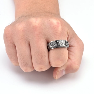 Detailed macro view of a vintage men's stainless steel ring with spinning leaf patterns