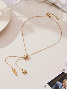 Détail des pendentifs pieuvre, hippocampe et étoile de mer sur un collier doré élégant