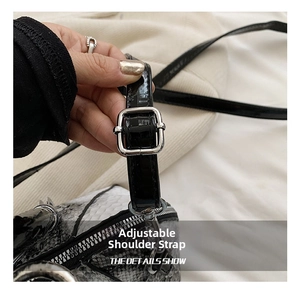 Detail of adjustable silver buckle and black faux snakeskin leather strap on a shell bag