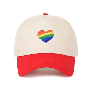 Dettaglio del ricamo a cuore arcobaleno su cappello trucker bicolore rosso e bianco