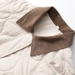 Detail of diamond quilted texture and brown corduroy collar on ivory cotton coat