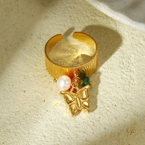 Detail of vintage gold ring with vertical texture, pearl, butterfly and green bead