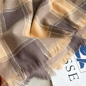 Close-up of khaki and brown plaid scarf with soft cashmere-like texture and tassel fringe
