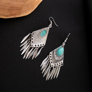 Macro detail of ethnic silver earrings with turquoise stones and pointed tassel pendants