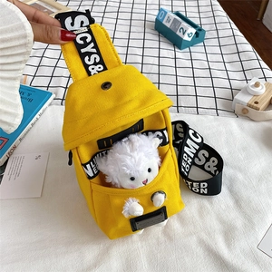 Detail of yellow canvas chest bag featuring a cute plush lamb doll in the front pocket