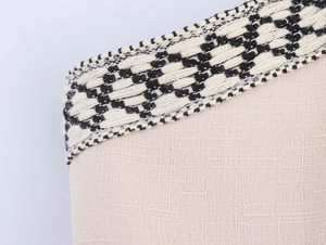 Dettaglio del tessuto in lino beige con passamaneria geometrica intrecciata bianca e nera