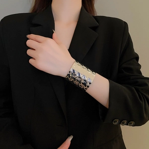 Model wearing a wide hammered silver bangle over a black suit showing irregular texture