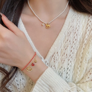 Detail of the multi-layer bracelet with red beads and golden rocking horse pendant