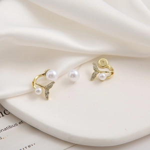 Detailed view of gold mermaid tail earrings featuring white pearls and sparkling zircon accents