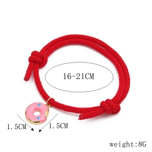 Detail of red braided Milan rope bracelet with a pink donut enamel charm and clear textures