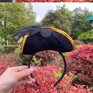 Detail view of a black velvet pirate hat headband with gold trim and feathers for Halloween
