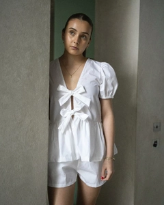 Détail du haut blanc à manches bouffantes avec nœuds et texture en tissu coton