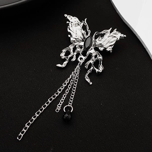 Gothic silver butterfly brooch with black gemstone and fringe chains on dark backdrop