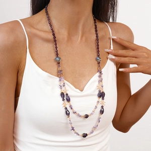 Detail of bohemian multilayer long beaded necklace with purple crystals and stones