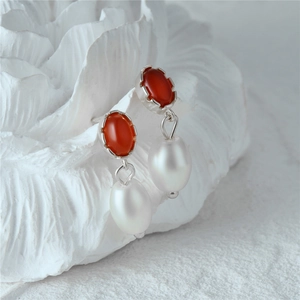 Detailed close-up of s925 silver earrings with red oval stones and waterdrop pearls