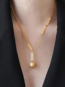 Detailed close-up of a golden necklace with matte frosted ball pendant and oval links