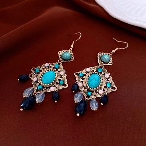 Détail de boucles d'oreilles bohèmes en forme de losange avec pompons sur satin marron