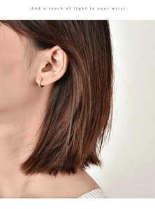 Close-up of minimalist gold hoop earring with pavé-set zircons worn on the ear