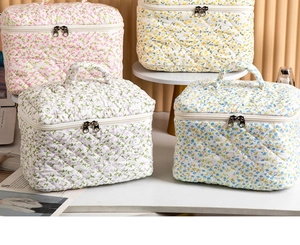 Close-up of quilted floral cosmetic bags in four pastel colors with dual zipper design