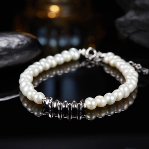 Detail of freshwater pearl bracelet with silver beads and lobster clasp on dark reflection
