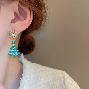 Close-up of snowflake and green Christmas tree tassel earrings with pearl details