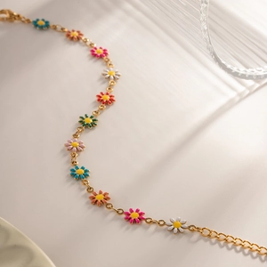 Detailed close-up of a gold titanium bracelet featuring colorful enamel daisy charms