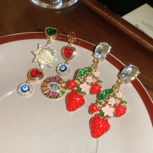 Detailed macro shot of vintage-style asymmetric heart and strawberry stud earrings set